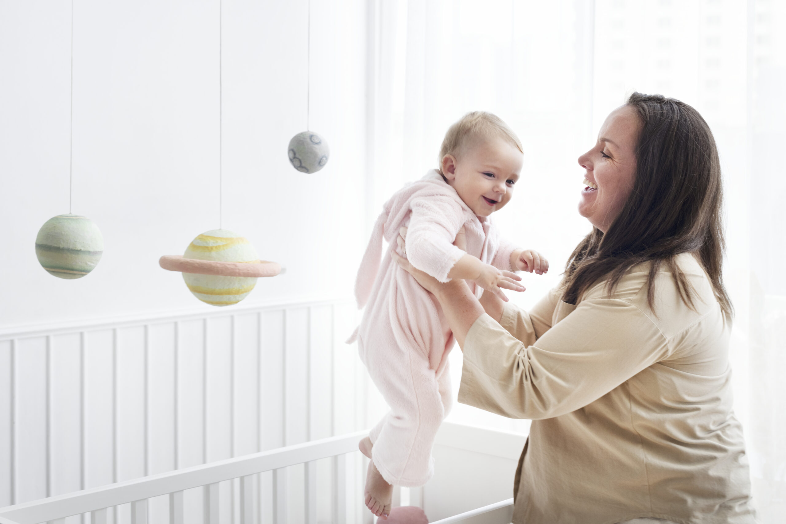 Mother lifting her baby out of her crib